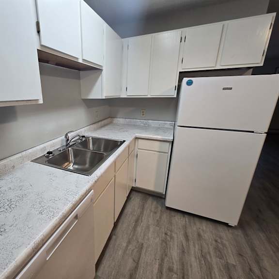 a kitchen with white cabinets and a white fridge.