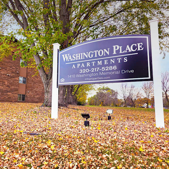 a sign for washington place apartments stands in front of a brick building.