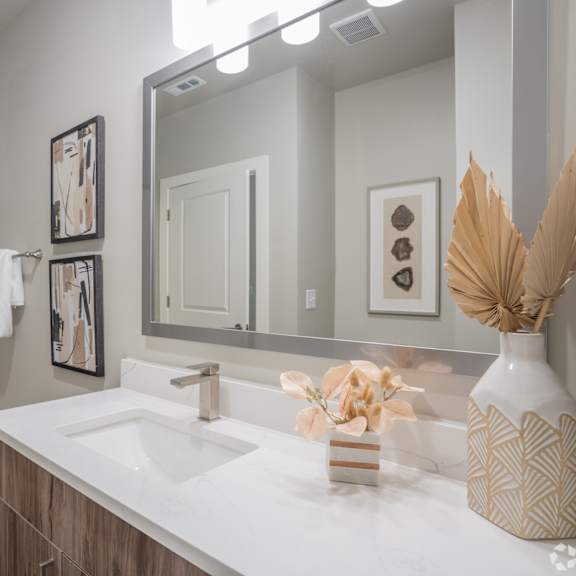 Thumbnail 6 of 9 A white sink in a bathroom with a white tub and a mirror.at The Delaney at East Park Apartments, Kennesaw