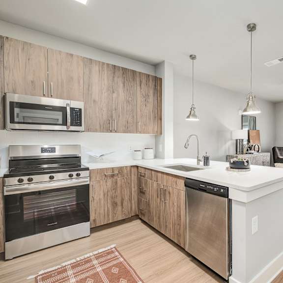 Thumbnail 1 of 13 A modern kitchen with wooden cabinets and stainless steel appliances.at The Ashton at East Park Apartments, Kennesaw, 30144
