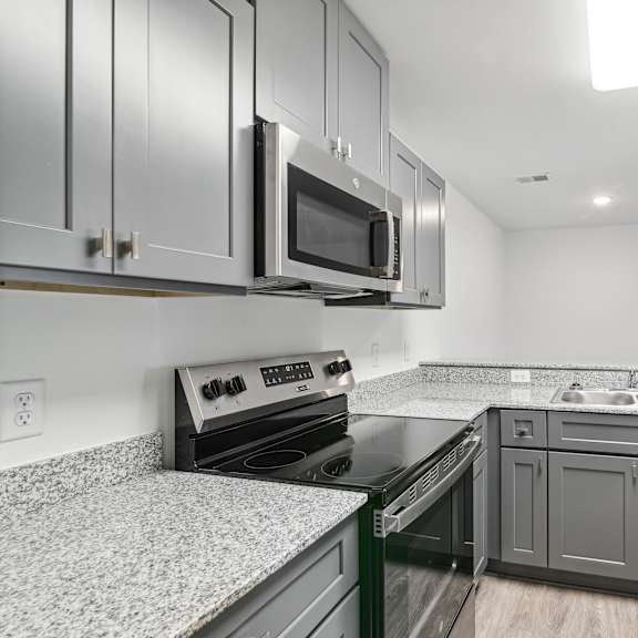Thumbnail 5 of 7 A kitchen with a stove, microwave, and refrigerator at The Parker North Augusta, North Augusta, SC, 29841