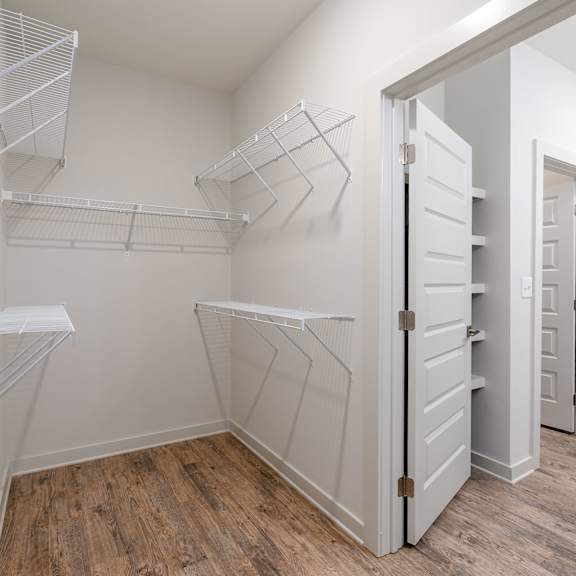 a white closet with shelves and a wooden floor.