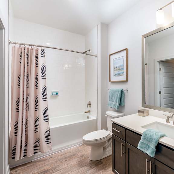 a bathroom with a white sink, toilet, and a shower with a pink shower curtain.