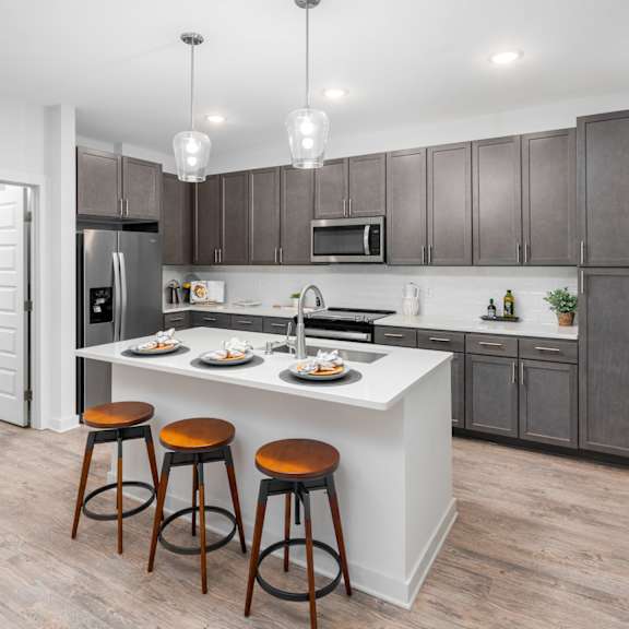 a kitchen with a white island and brown bar stools.