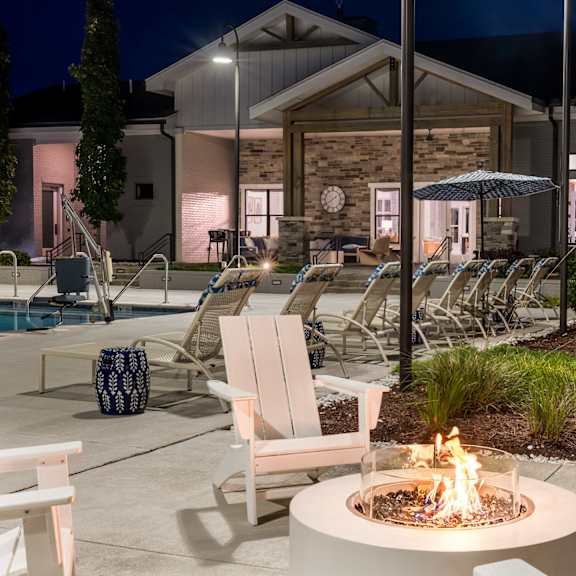 a fire pit sits in the middle of a patio surrounded by chairs.