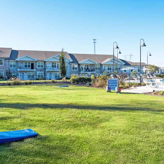 a grassy field with a blue tarp and a white building in the background.