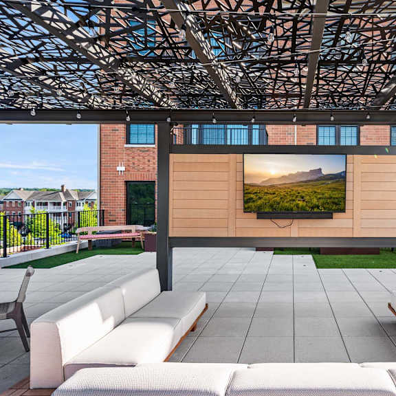 a modern outdoor seating area with a large screen displaying a landscape.