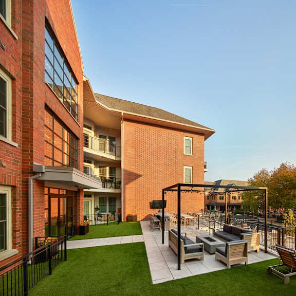 a modern outdoor seating area with a black metal pergola and wooden chairs.