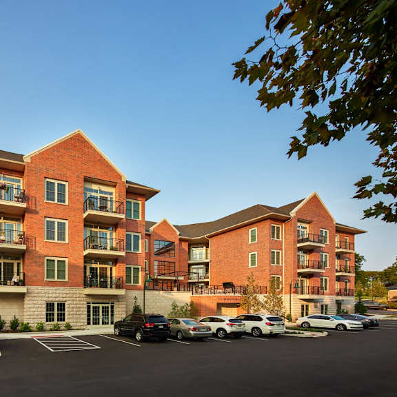 a large red brick apartment building with a parking lot in front.