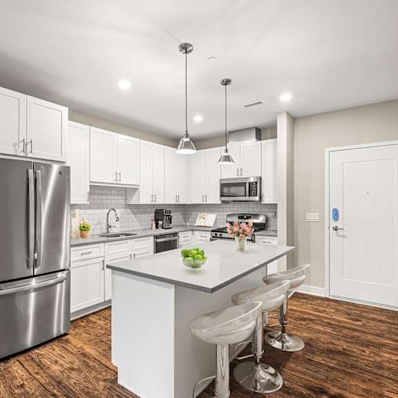 a modern kitchen with white cabinets and a wooden floor.