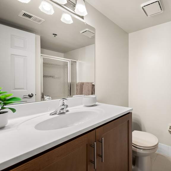 a bathroom with a toilet, sink, mirror, and towel rack.