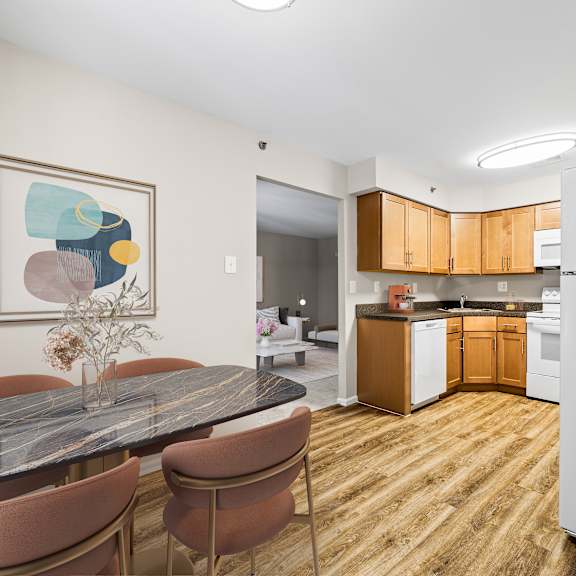 a kitchen with a table and chairs in the foreground and a refrigerator in the background.