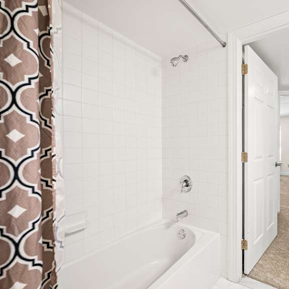 a bathroom with a white tub and a shower with a brown and white shower curtain.