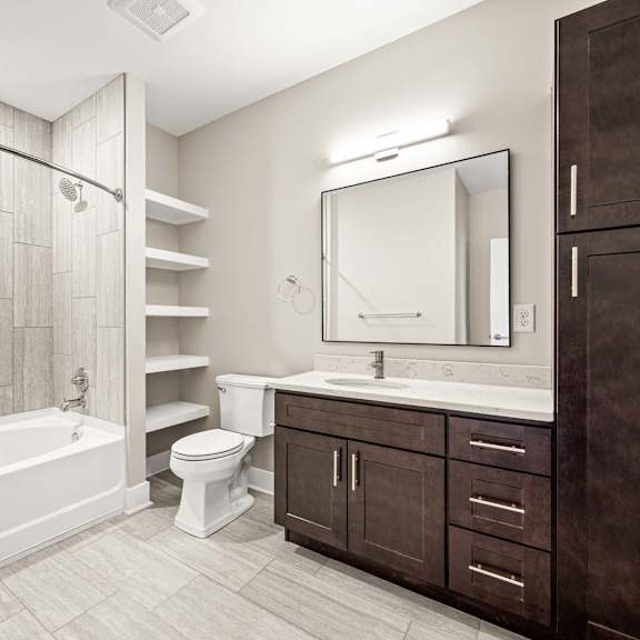 a bathroom with a tub, toilet, sink, and mirror.