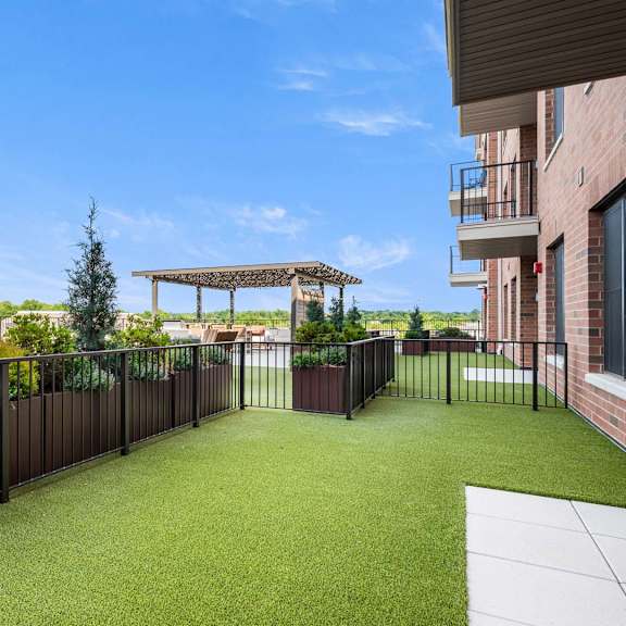 a patio with a black fence and a green lawn.