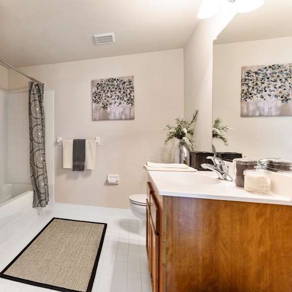 clean and simple bathroom featuring a white door, toilet, sink, and a soft rug on the floor at claremont apartments in exton, pa