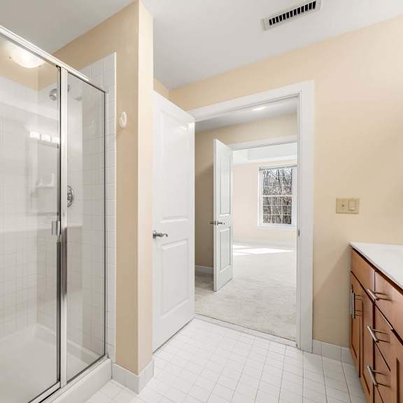 a bathroom with a glass shower door and a white tiled floor.