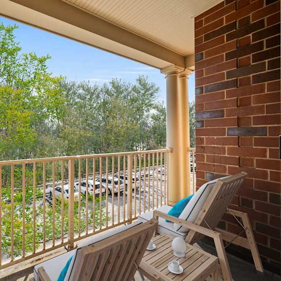 a balcony with a chair and a table with a cup on it.