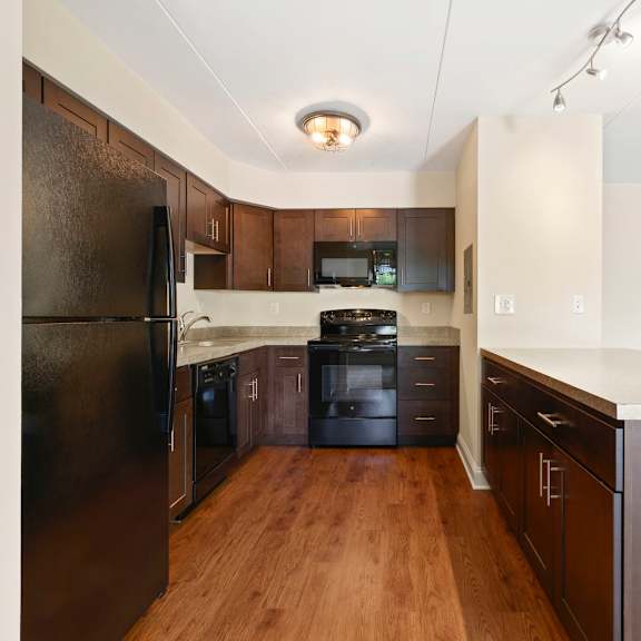 an empty kitchen with black appliances and wood floors