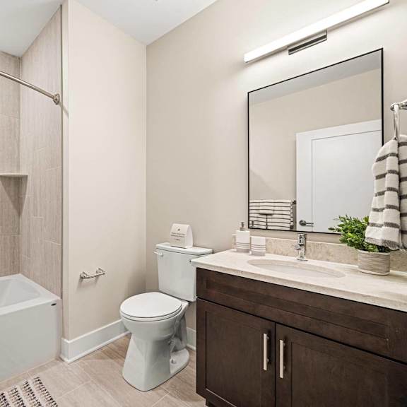 contemporary bathroom featuring a walk-in shower, toilet, sink, and stylish mirror at hamilton at eagleview in exton, pa