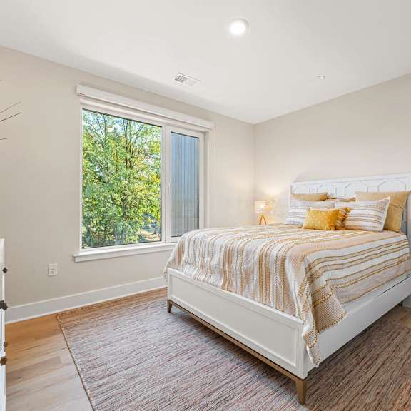 cozy bedroom featuring a comfortable bed and a large window allowing natural light at hamilton at eagleview in exton, pa