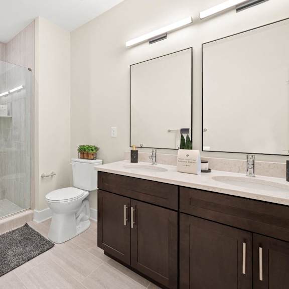 modern bathroom with a walk-in shower, toilet, sink, and large mirror at hamilton at eagleview in exton, pa