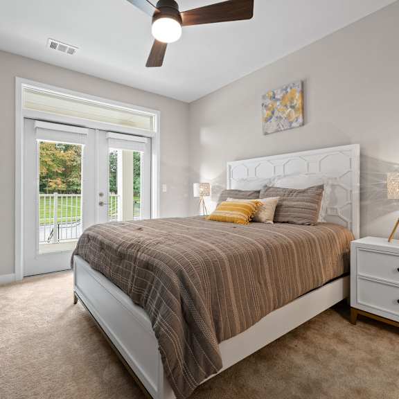 cozy bedroom featuring a comfortable bed and a door leading to a private patio at hamilton at eagleview, exton, pa 19341