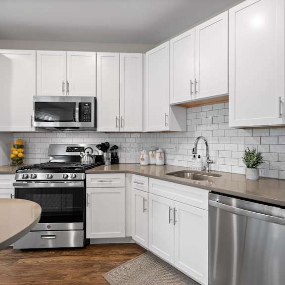 contemporary kitchen with white cabinetry, stainless steel appliances, and sleek finishes at hamilton at eagleview in exton, pa