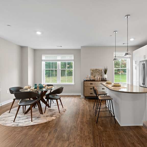 modern kitchen with a central island and a dining table with chairs at hamilton at eagleview, exton, pa 19341
