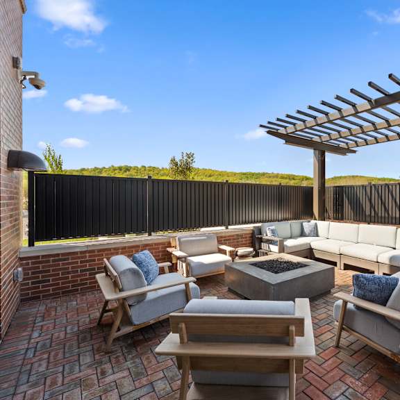 an outdoor patio with comfortable furniture, a fire pit, and a pergola.
