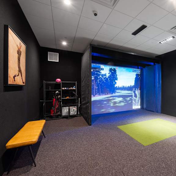 a multi-sport simulator projector screen in a community room with sports equipment.