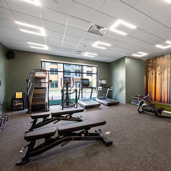 a spacious fitness room with cross training weight and cardio equipment and a large window.