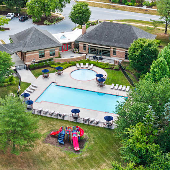 an aerial view of a pool surrounded by trees and a building.