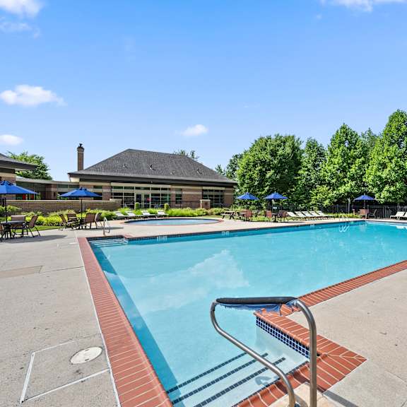 a pool surrounded by trees and a building in the background.