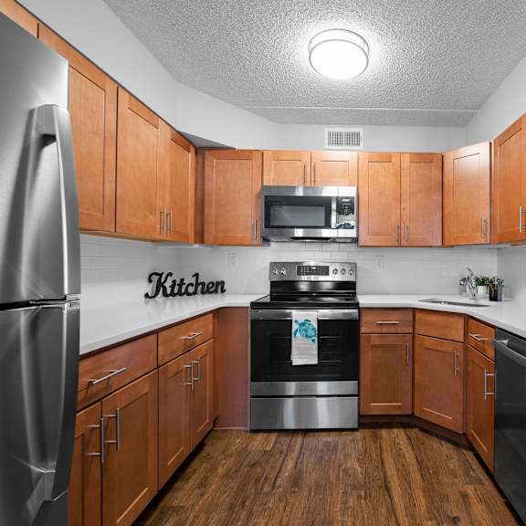 stylish u-shaped kitchen with stainless steel appliances, a sleek subway tile backsplash, durable quartz countertops, and elegant hardwood-style flooring at new kent apartments, west chester, pa