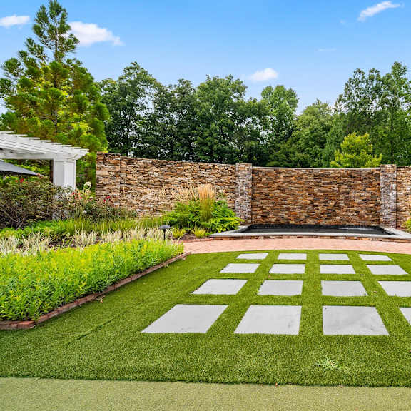 a garden with a white lawn and a stone wall.