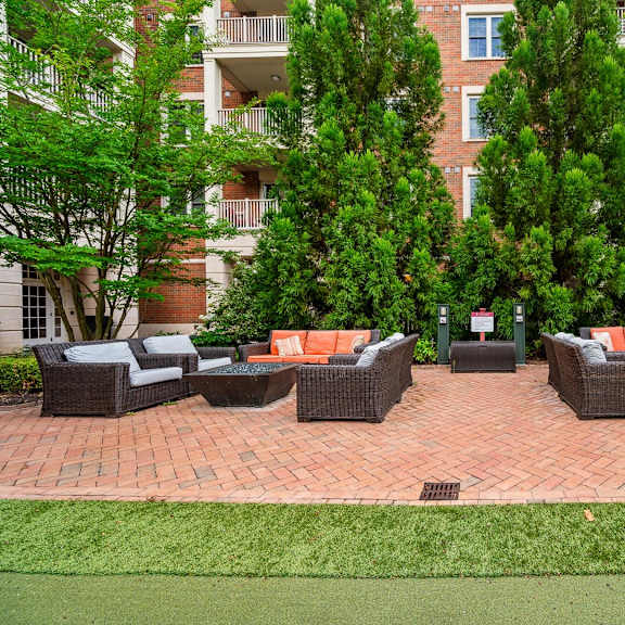 a patio with a table and chairs is surrounded by trees and apartment buildings.