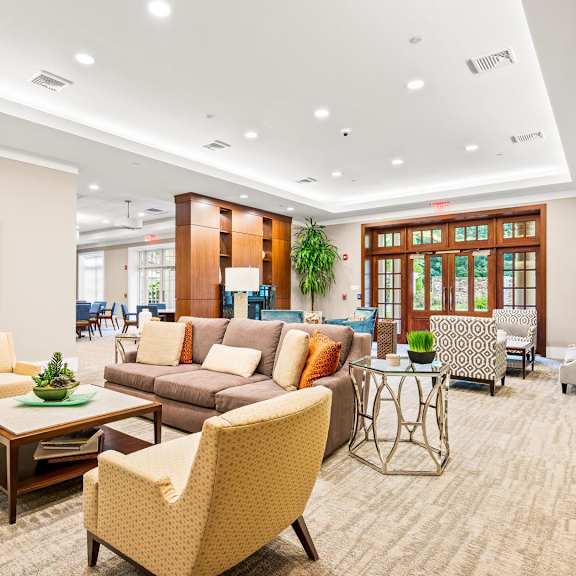 a living room with a large painting on the wall and a variety of furniture including a sofa, armchair, and coffee table.