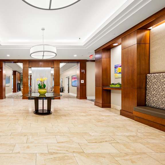 a hallway with a table in the middle and a chandelier hanging from the ceiling.