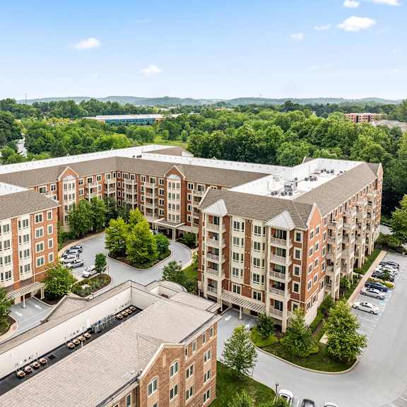 a large apartment complex with a parking lot in front.