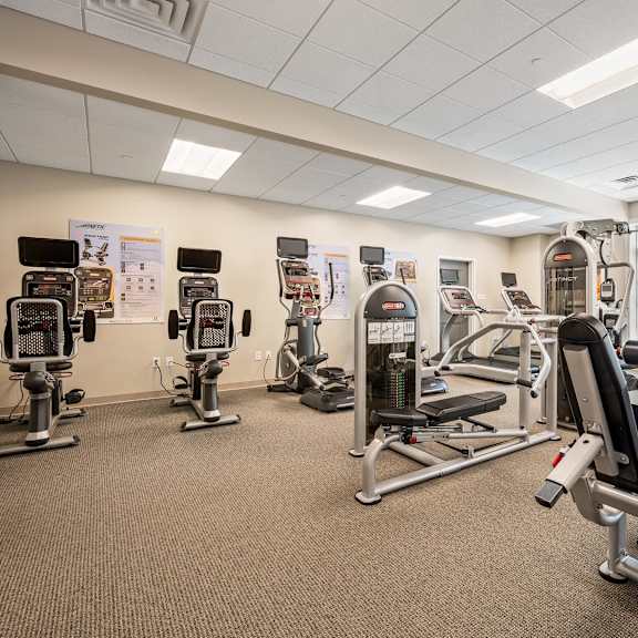 a gym with a variety of equipment including treadmills, weights, and exercise machines.