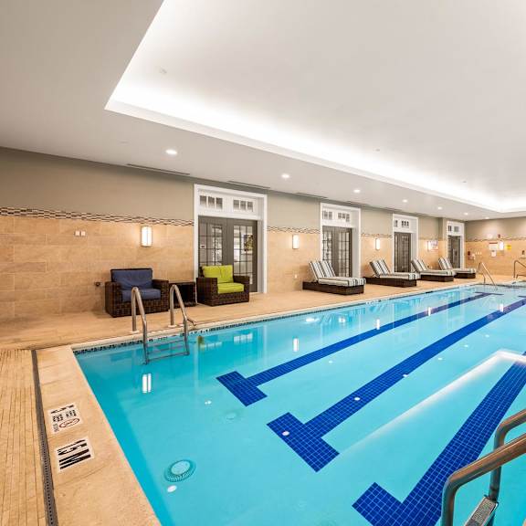 a large indoor swimming pool with blue lanes and a wooden floor.