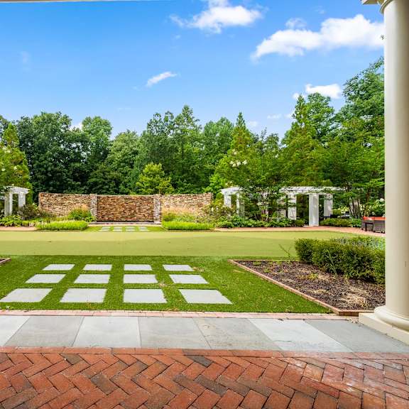 a garden with a brick pathway leading to a white archway.