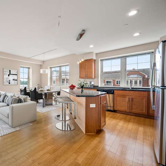 a modern kitchen with a refrigerator, sink, and wooden cabinets.