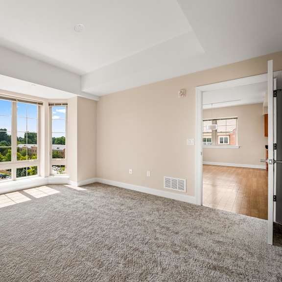 a spacious room with a carpeted floor and a view of the outside through the windows.