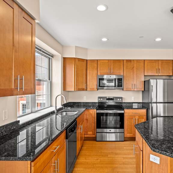 a kitchen with wooden cabinets and black countertops.