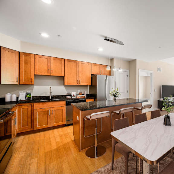 a modern kitchen with wooden cabinets and a dining table with chairs.