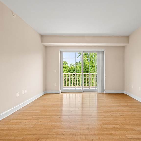 a room with wooden floors and a sliding glass door leading to a backyard.