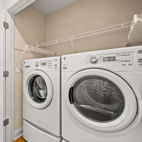 a white door is open to reveal a laundry room with a washer and dryer.