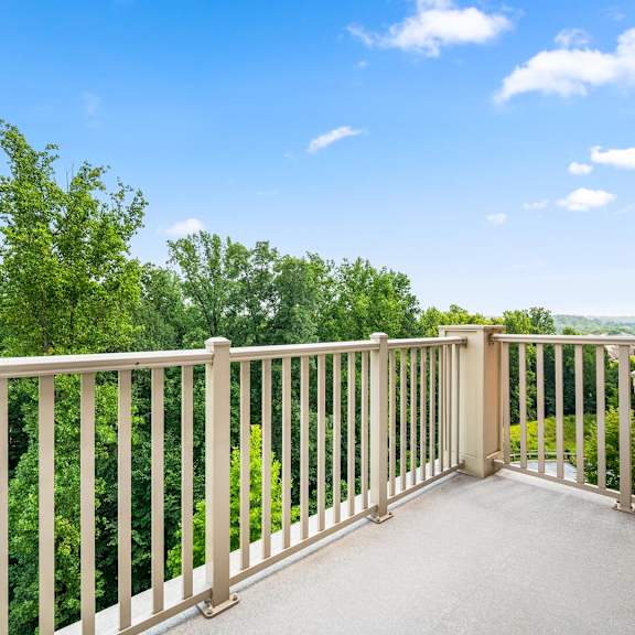 a balcony with a railing overlooking a green landscape.